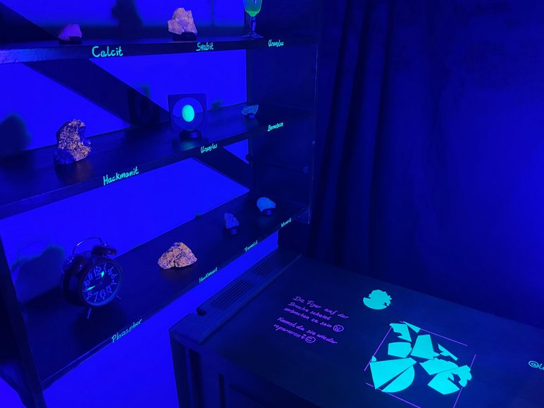 Dunkler Ausstellungsraum im UV-Licht, das ausgestellte Gesteine und Mineralien leuchten lässt