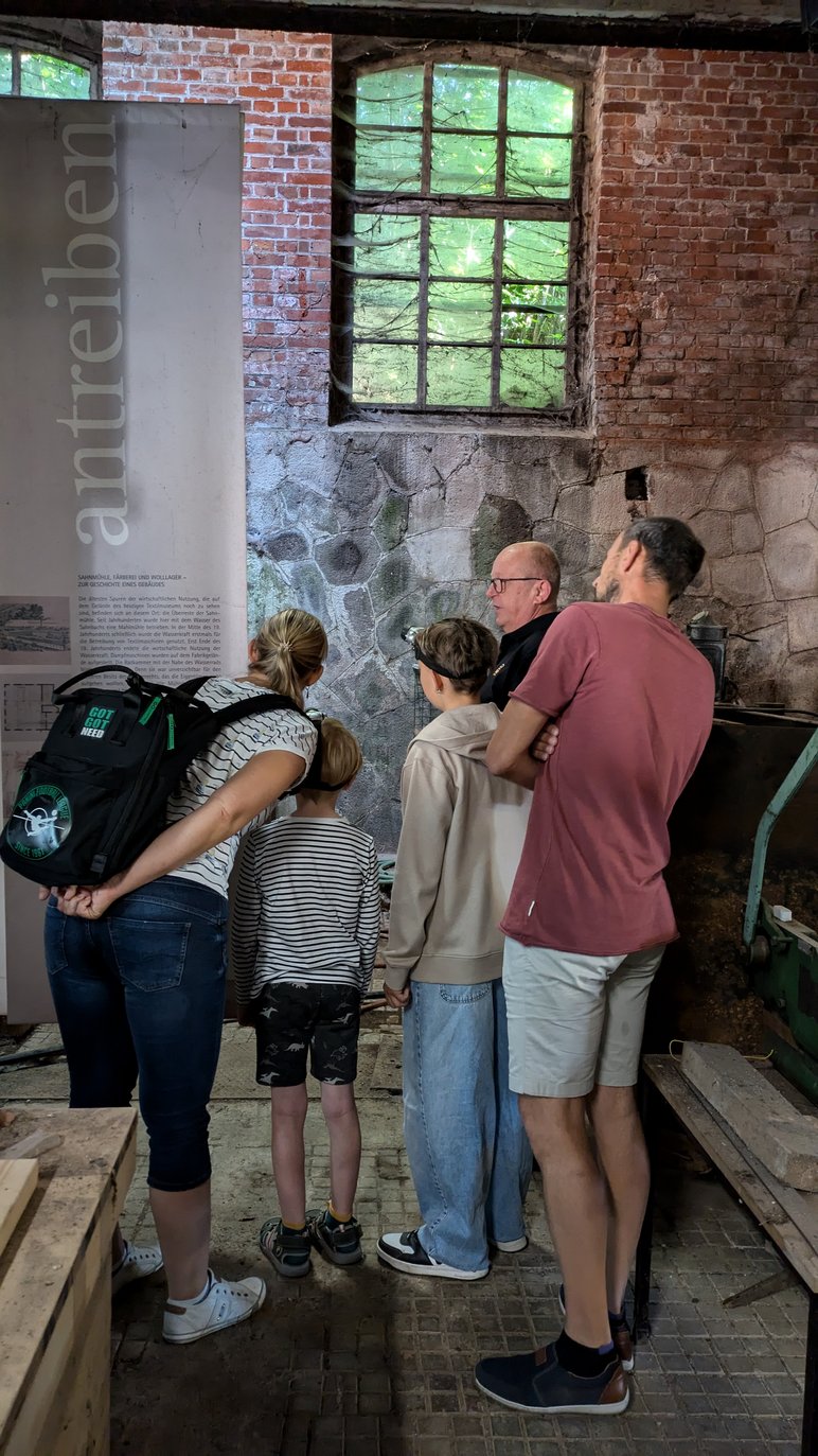 Blick zum ehemaligen Wasserrad Eine Familie blickt auf das in der Mauer verbauten Wasserrad in der ehemaligen Mühlkammer