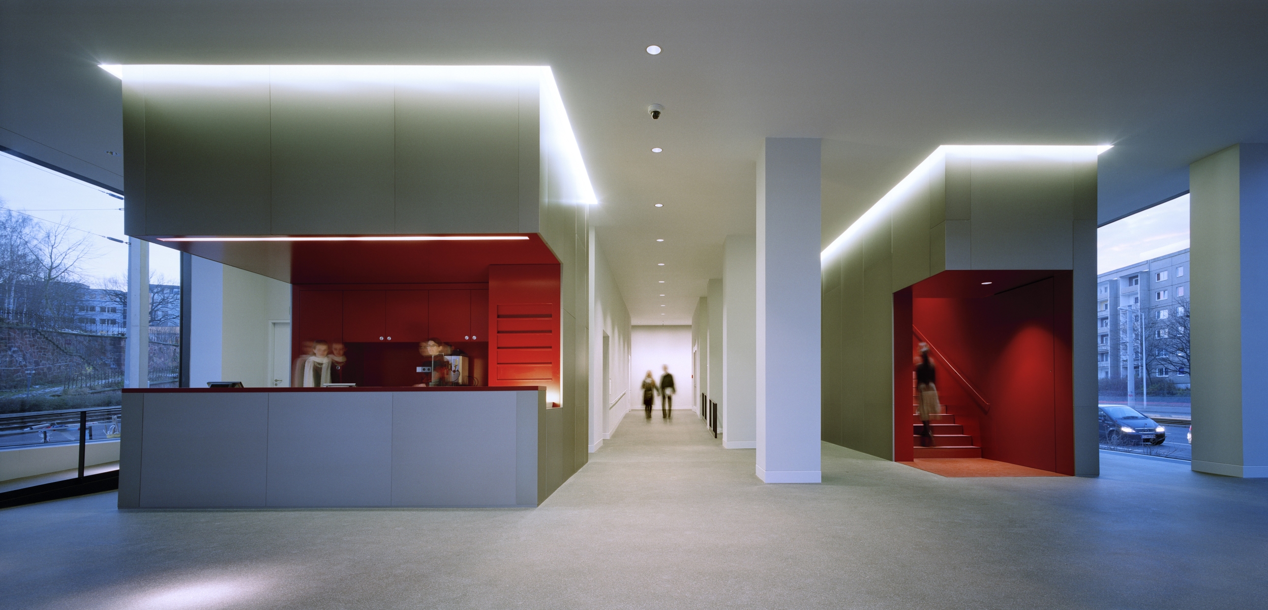 Das Foto zeigt das in Weiß gehaltene Foyer des Museum Gunzenhauser. Links und rechts öffnen bodentiefe Panoramafenster die Sicht nach außen. Innen, auf der linken Seite, befindet sich die Kasse; mittig schließt sich ein langer Gang zu den Ausstellungsräumen im Erdgeschoss an. Rechts des Ganges befindet sich das schmale, steile Treppenhaus, das in die Ausstellungräume in den Obergeschossen führt. Kasse und Treppenhaus sind in einem tiefen Rot gehalten.